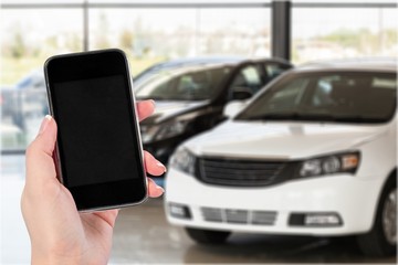 Hand holds phone and car.