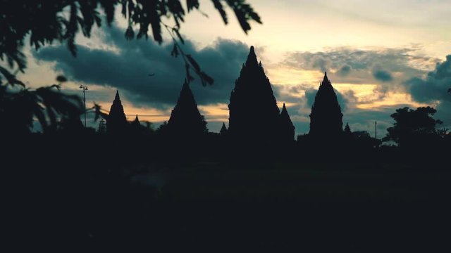 Prambanan temple, tree and plane silhouette on sunset in Jogjakarta, Indonesia