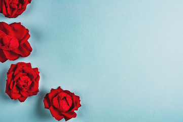 Row of four red roses on blue background. Love concept