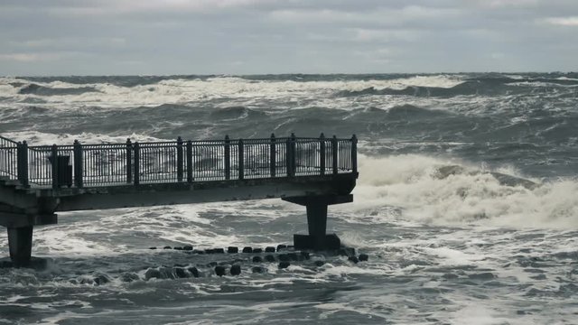 High wave breaking on the rocks of the coastline. Stormy weather on sea with big wave breaking on breakwater. Slow Motion.