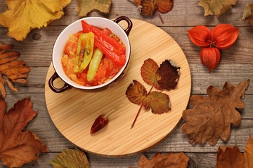 Hungarian Lecso - pepper and tomato stew with autumn leaves and physalis on wooden background