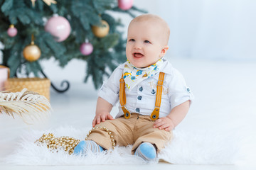 Little boy sitting on the background of the Christmas tree