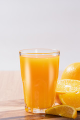Glass of orange juice with fresh fruits on wooden floor