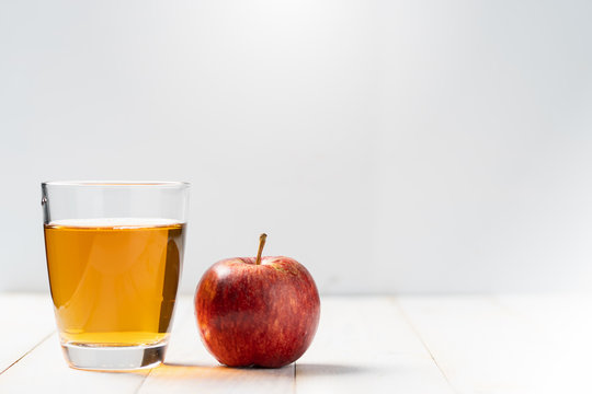 Fresh apple juice in the glass on wooden floor.
