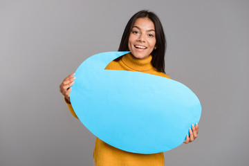 Fototapeta premium Happy woman posing isolated over grey wall background holding speech bubble.