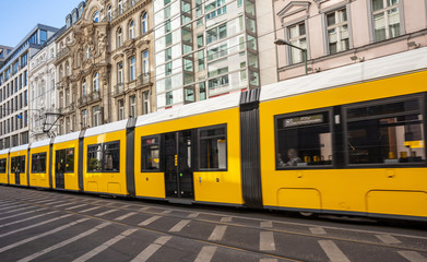 Fototapeta na wymiar Yellow tram in the city center, office buildings background