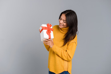 Excited woman posing isolated over grey wall background holding box surprise present.