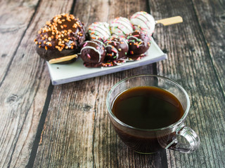 Colorful donuts and black coffee on wooden table. Morning breakfast.