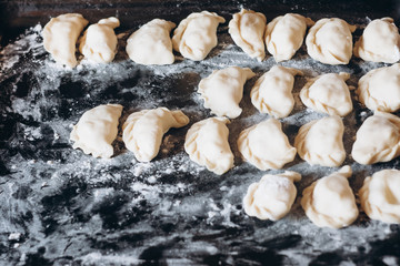 Dumplings raw on a dark board. Traditional homemade food.  Process of cooking dumplings. 