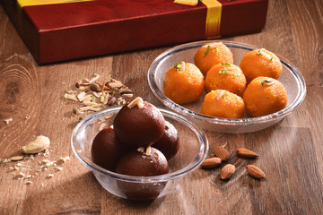diwali sweets concept, ladoo and gulab jamun on wooden table with sweets box in background