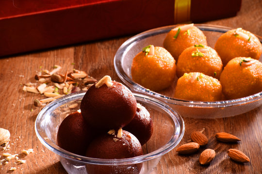 Gulab Jamun And Ladoo In Transparent Bowl With Dry Fruits And  Sweets Box Background