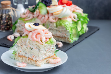Piece of traditional savory swedish sandwich cake Smorgastorta with bread, shrimps, eggs, caviar, dill, mayonnaise, cucumber and lettuce, horizontal, copy space