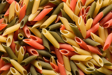 Close-up of raw and colorful penne pasta, a decorated pattern background