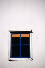Abstraktes Fenster  / Ein abstraktes Fenster mit blauem Fensterrahmen und orangener Jalousie im Sonnenlicht..