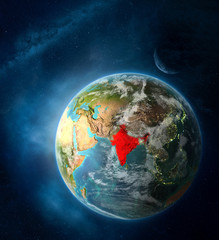 India from space on Earth surrounded by space with Moon and Milky Way. Detailed planet surface with city lights and clouds.