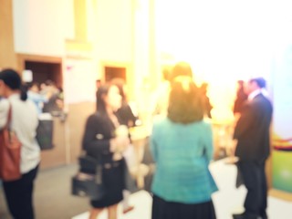 blurred image of people walking on a trade fair exhibition or expo where business people show...