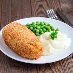 Chicken Kiev, ukrainian cuisine. Chicken cutlets in breadcrumbs stuffed with butter and herbs, served with mashed potato and green peas, square format