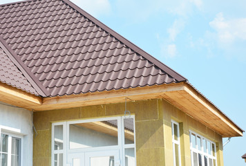 Metal roofing construction with rock wall wall insulation. Unfinished soffit boards installation.
