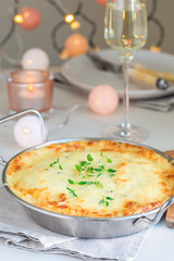 Cheesy scalloped potatoes or potato gratin in a baking dish, holiday theme, vertical
