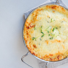 Cheesy scalloped potatoes or potato gratin in a baking dish, holiday theme, square format, top view, copy space