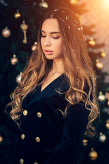 Holidays, celebration and people concept - young woman in elegant dress over christmas interior background.