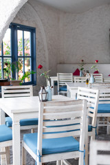 Interior of greek restaurant with white and blue chairs. Bali island greek restaurant.