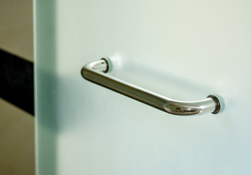 Glass door handle of a glass partition shower unit. Bathroom glass door detail with selective focus 