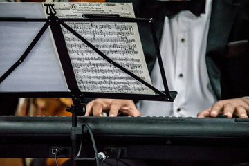 musico tocando el piano con traje negro y notas musicales en partitura, musica concierto, alegria