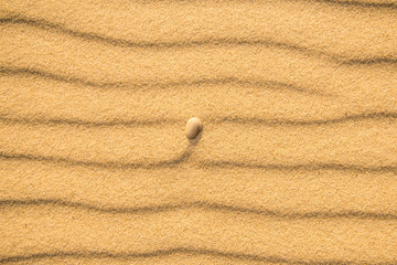 Fototapeta na wymiar Sand of a beach with pebble and wave patterns