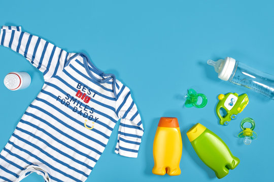 Baby care with bath set. Nipple, toy, clothes, shampoo on blue background top view mockup