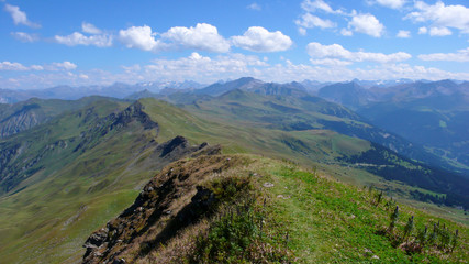 scenic summer mountain landscape with green hills and mountain peaks and a faint hiking trail in...