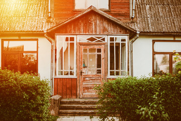 Old red house with wooden elements in Latvia, Europe. Entrance of the home, green bushes at sides....