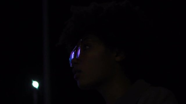 Stylish woman attentively looking at illuminated billboard reflection in glasses