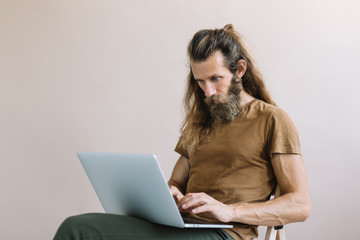 Stylish and creative man copywriter with beard and mustache using laptop computer and internet, working project online. Portrait of freelancer developer typing on keyboard. Successful business