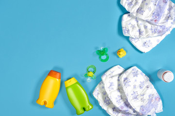 Baby care with bath set. Nipple, toy, diapers, shampoo on blue background top view mockup