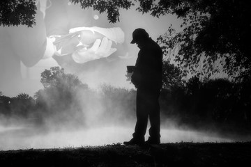 This black and white photo illustration shows an adult male reflecting on past military service and lost companions on Veteran's Day or Memorial Day.