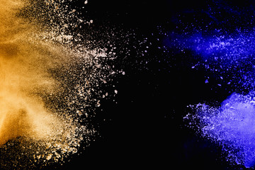 Yellow-blue powder explode cloud on black background. Launched yellow-blue dust particles splash on  background.