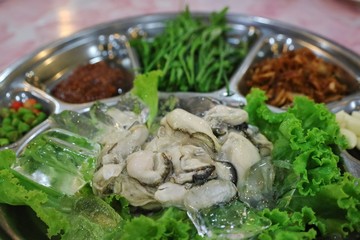 Oysters with herbs, fried sliced garlic, chilli and the dipping spicy sauce. Thai style seafood. Selective focus. Food concept.