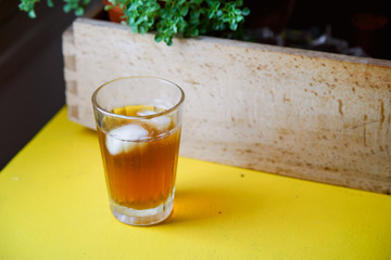 Summer coffee cocktail with tonic and ice cubes on a yellow table