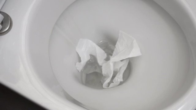 White toilet paper is flushed down the toilet.

