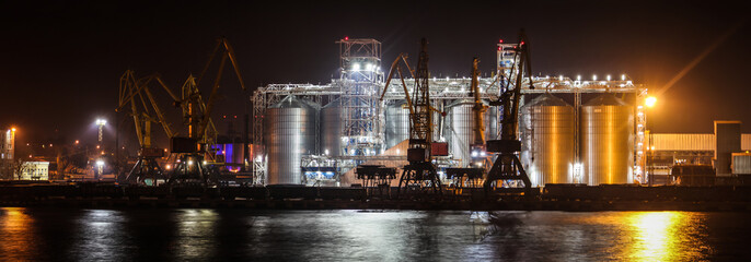Loading grain in the port. Night panoramic view of the port, cranes and other port infrastructure.