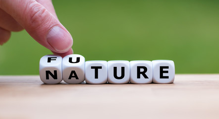 Hand is turning a dice and changes the word Nature to Future