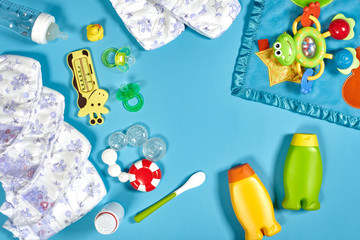 Baby care with bath set. Nipple, toy, diapers, shampoo on blue background top view mockup
