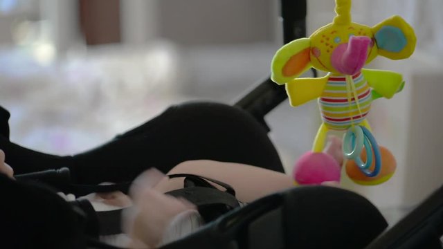 A baby in a stroller plays with a soft toy.