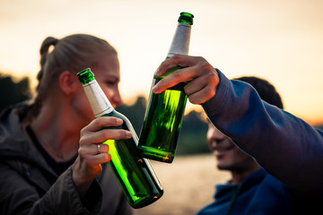 Close-up of couple clinking their beer bottles outdoors