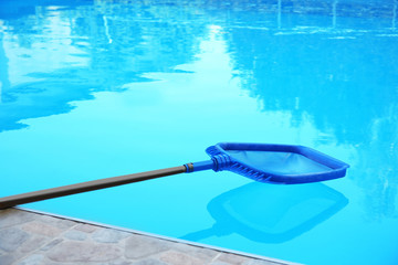 Cleaning outdoor pool with scoop net, closeup