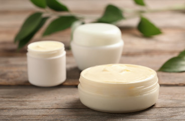 Fototapeta na wymiar Closeup view of hand cream jars on wooden background