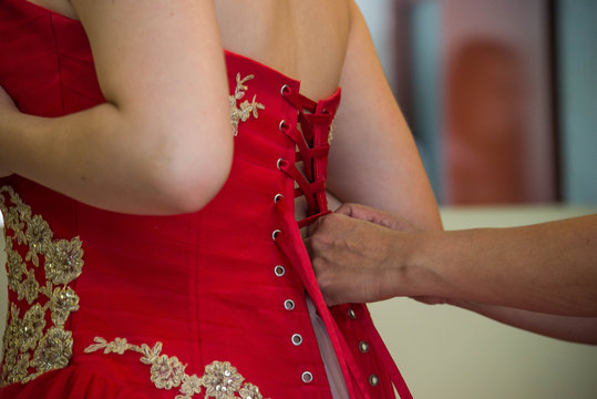 manos amarrando vestido rojo de joven latina con corset en color rojo y  agujetas Stock Photo | Adobe Stock