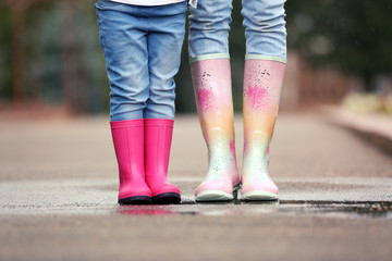 Mother and daughter wearing rubber boots on street, closeup