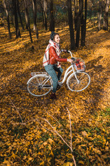Naklejka premium high angle view of girl in leather jacket and beret riding on bicycle in yellow autumnal forest